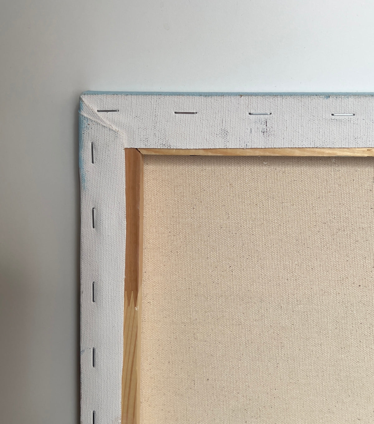 Close-up of a framed painting with a beige canvas and metallic frame on a neutral background