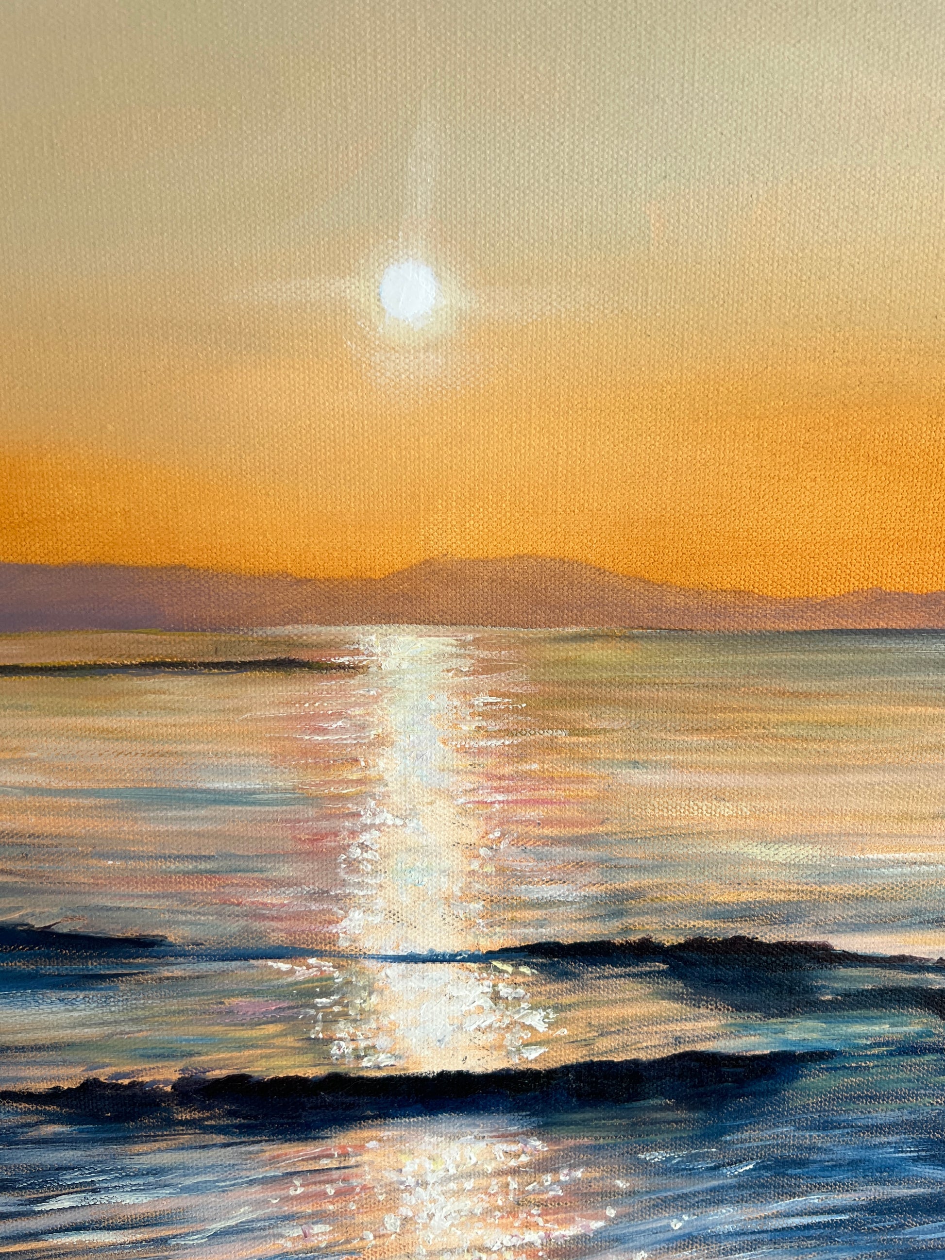 Sunset over water with a bright sun in the sky