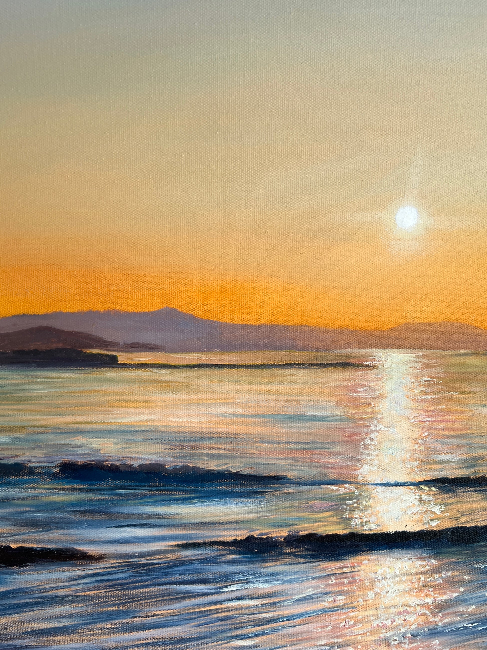 Sunset over a body of water with mountains in the distance