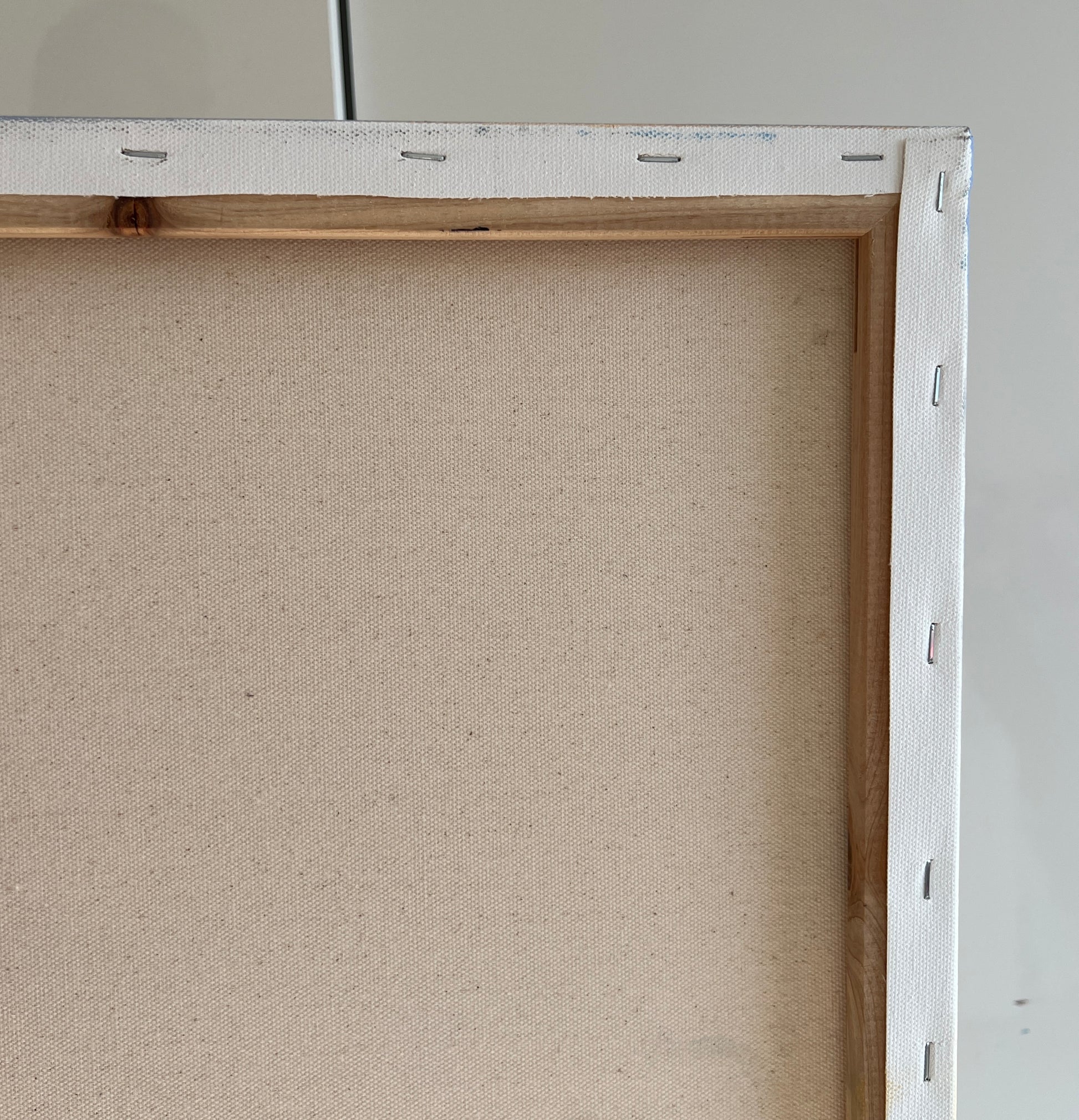 Close-up of a back of the canvas with a wooden frame on a gray background