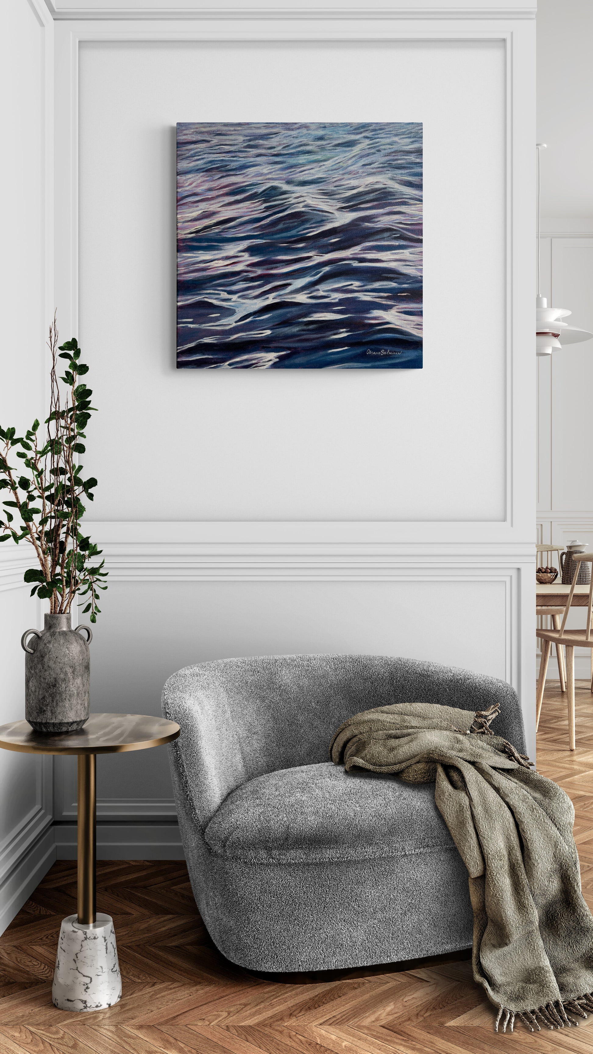 Gray armchair with a blanket in a room with a wall painting of wavy lines.