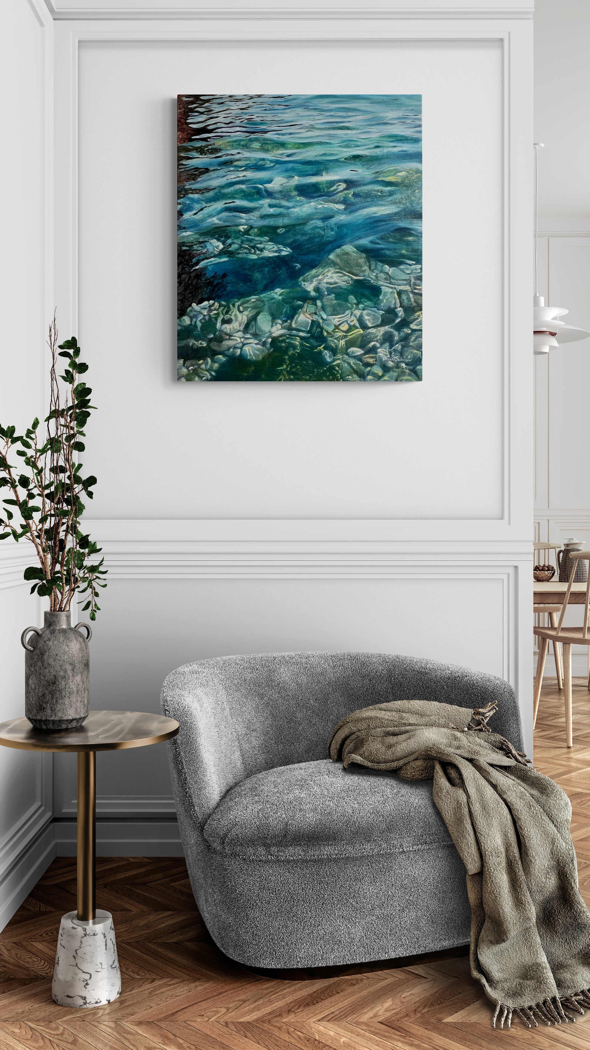 Gray armchair with a blanket in a room with a wall painting of water.