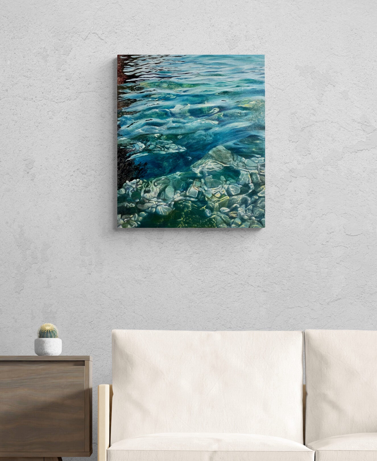 Canvas print of water scene hanging on a wall above a sofa.