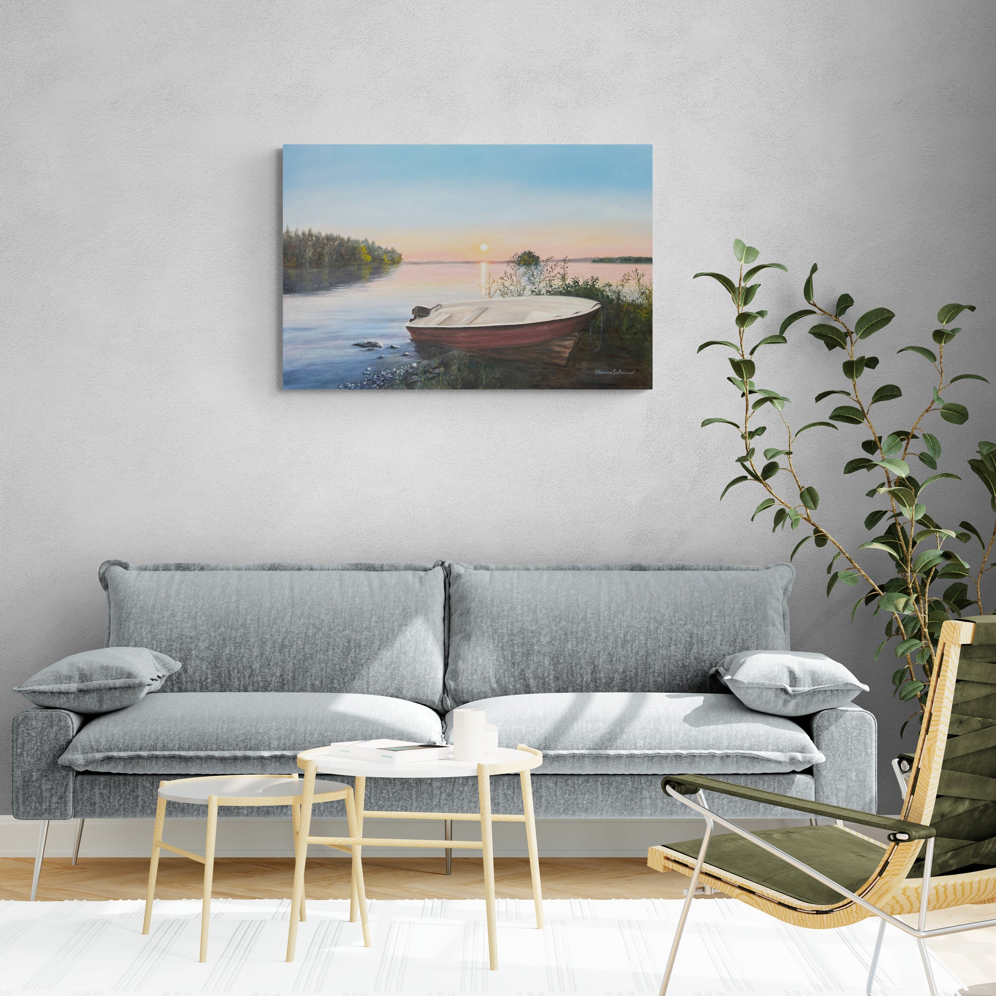 Living room with a gray sofa, small table, and chair, featuring a painting of a lake and boat on the wall.