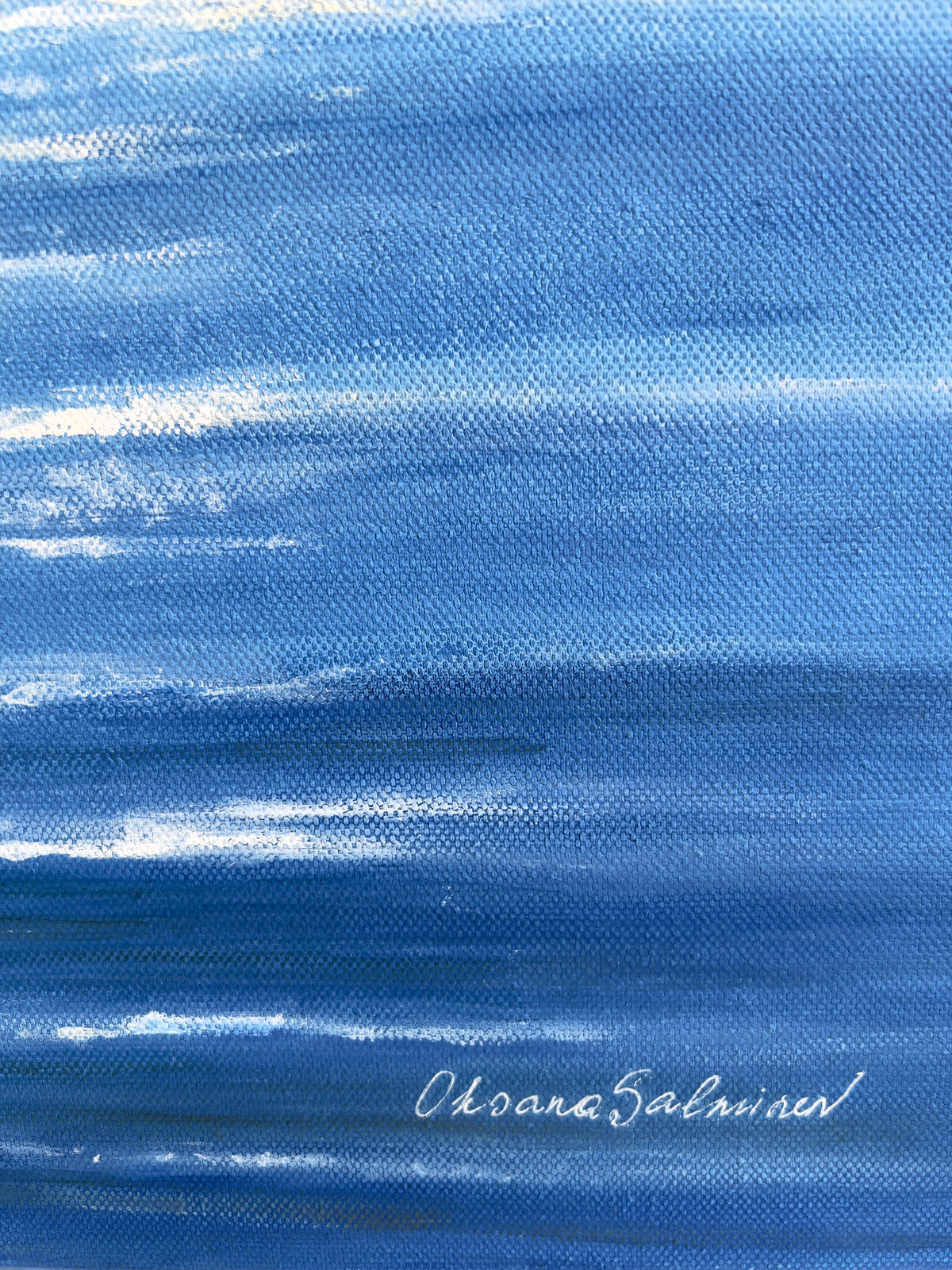 A close-up of a blue painted canvas or textured print with horizontal brushstrokes and a white script signature near the lower right reading 'Oksana Salminen'.