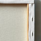 Close-up of a canvas wall art frame showing the textured off-white fabric border, wooden stretcher bars, and hanging holes.
