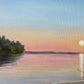 Sunset over a lake with trees on the shore