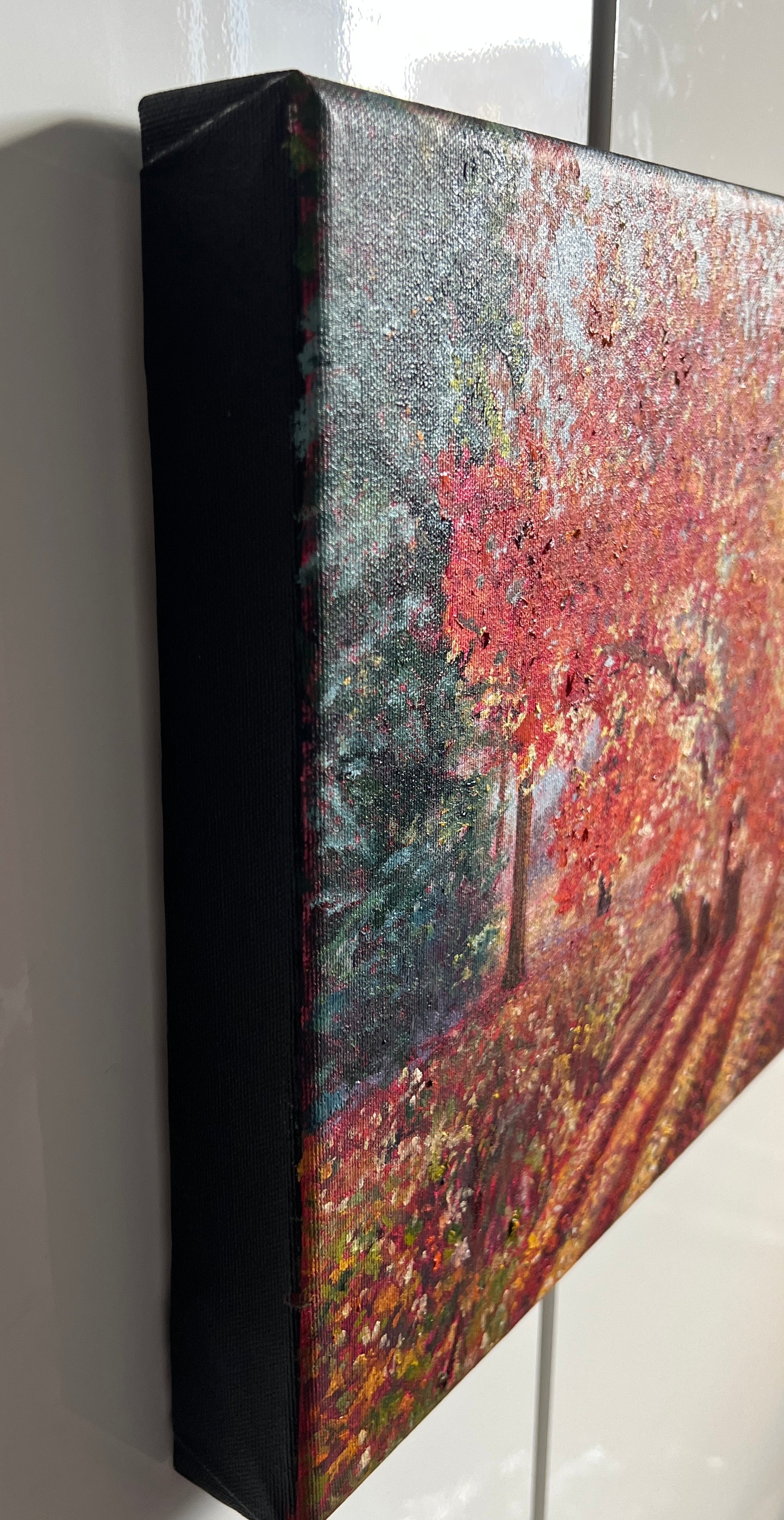 Oil painting of a landscape with trees and flowers on a white wall.