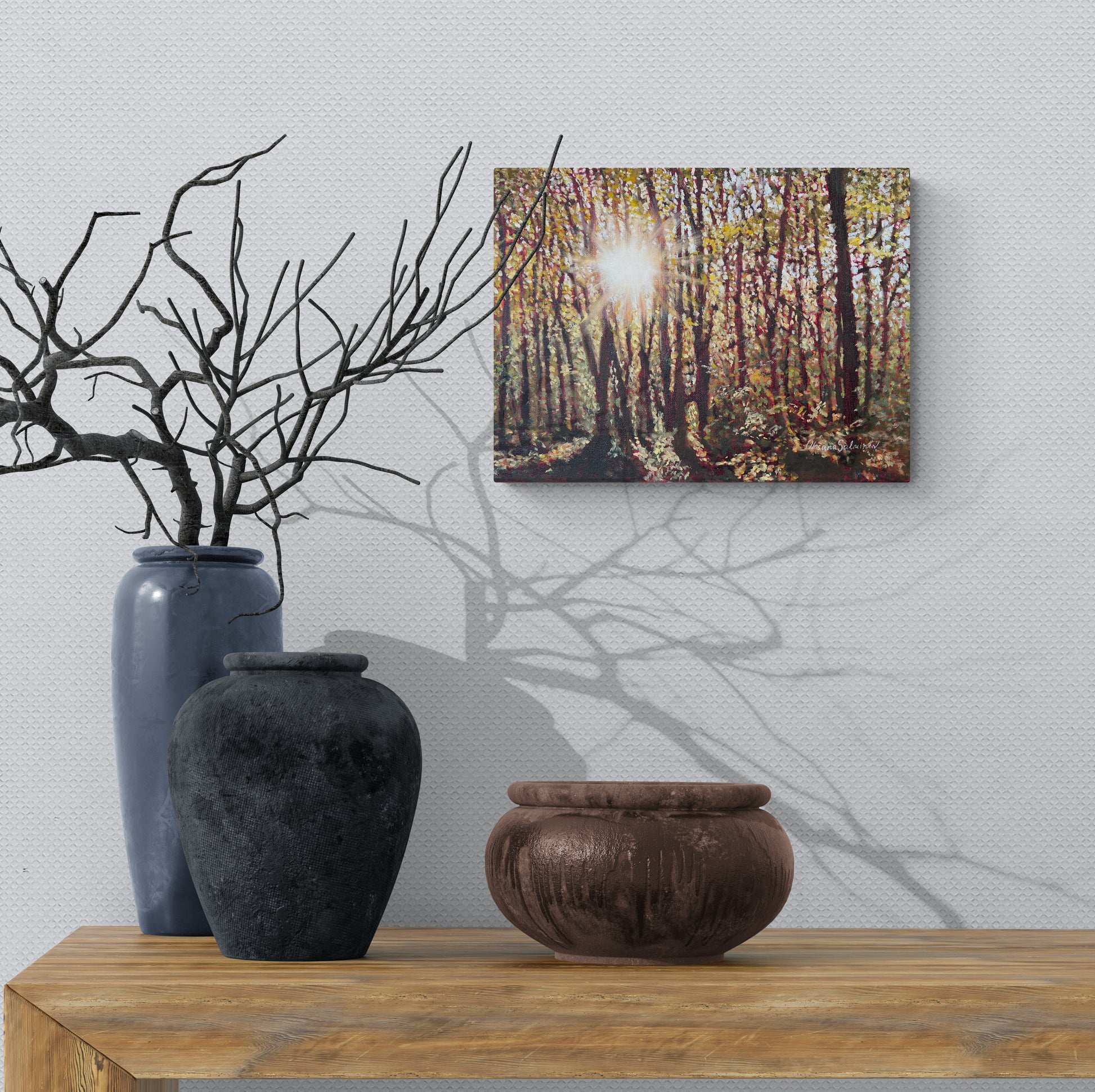 Decorative setup with vases and a forest painting on a wall.