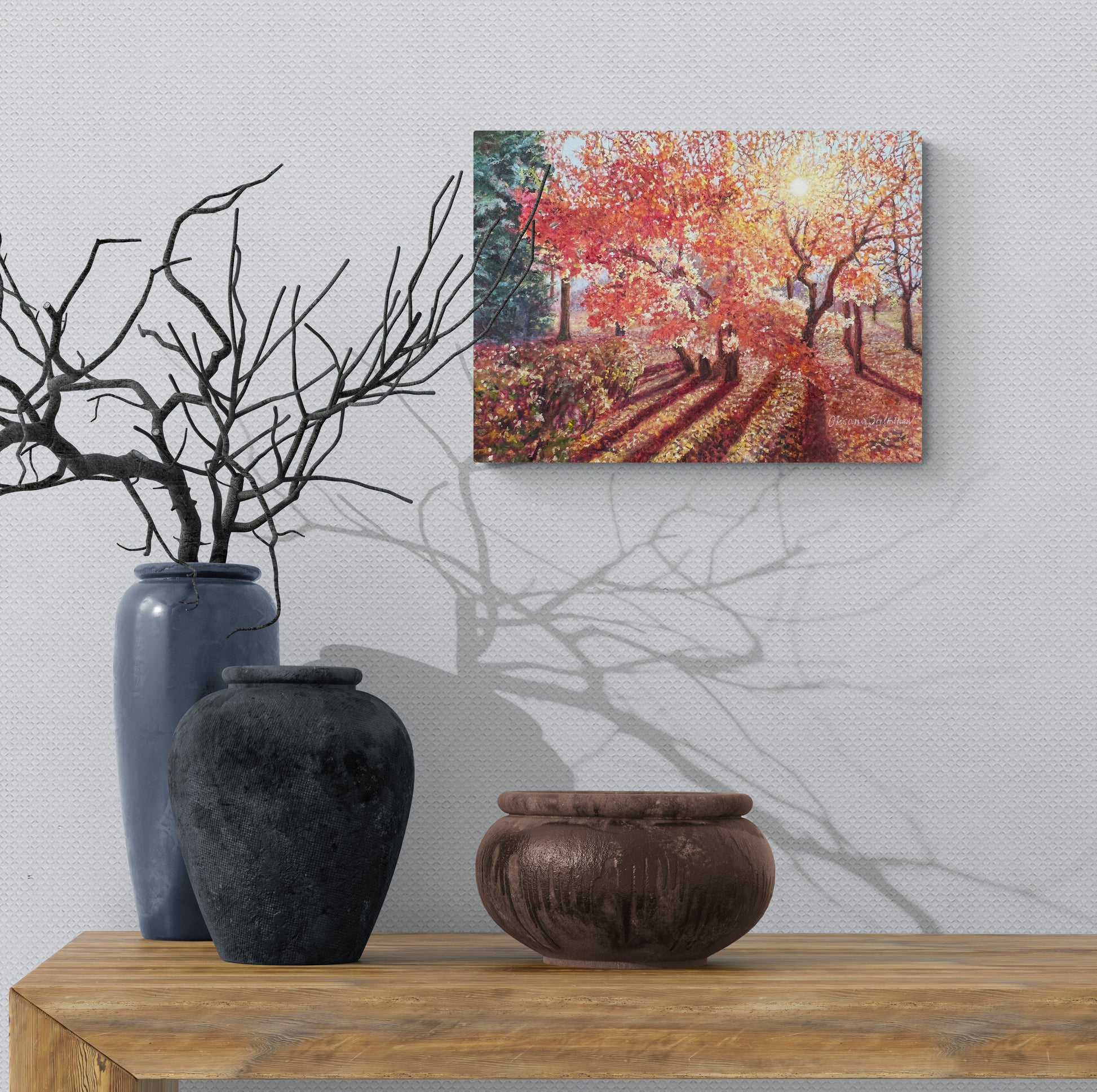 Decorative setup with vases and a painting of a autumn scene on a wall.