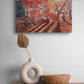 Oil painting of an autumn scene on a wall above a wooden shelf with decorative items.