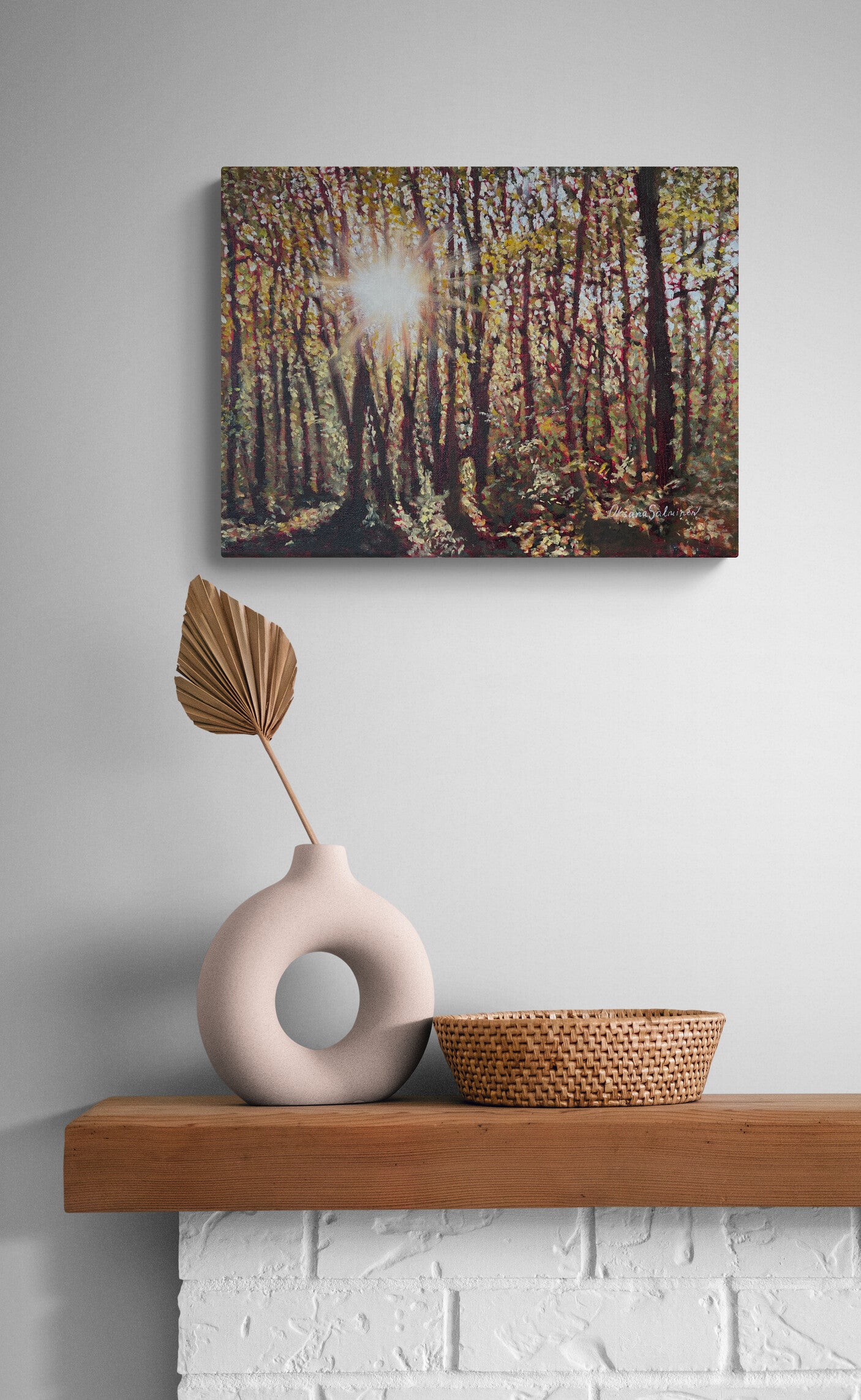 Canvas print of a forest scene above a wooden shelf with a vase and basket.