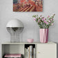 Decorative shelf with books, a vase of flowers, and a painting on a gray wall.