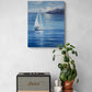 A vertical canvas print of a blue seascape with a white sailboat, displayed on a textured light gray wall above a console table with a Marshall speaker and a potted plant.