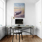 Modern home office with a desk, chair, and wall art of a boat.