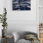 Gray armchair with a blanket in a room with a wall painting of wavy lines.