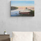 Painting of a boat on a lake with a sunset, hanging on a wall above a sofa.