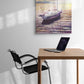 Sailing boat painting on a wall above a desk with a chair.