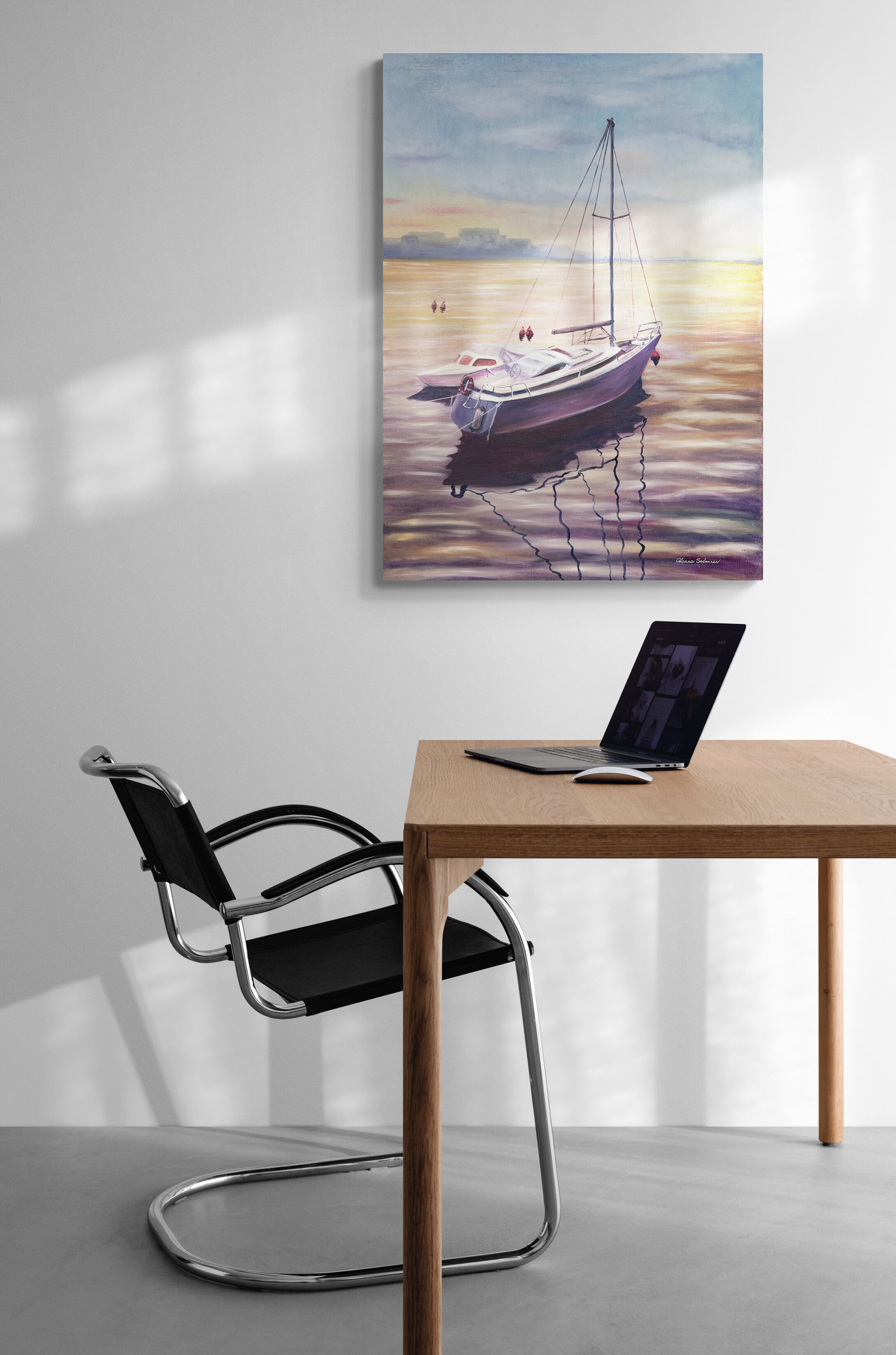 Sailing boat painting on a wall above a desk with a chair.