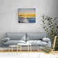 Original oil painting on canvas depicting a sunset over water, styled in a modern living room setting above a gray fabric sofa.