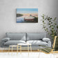 Living room with a gray sofa, small table, and chair, featuring a painting of a lake and boat on the wall.