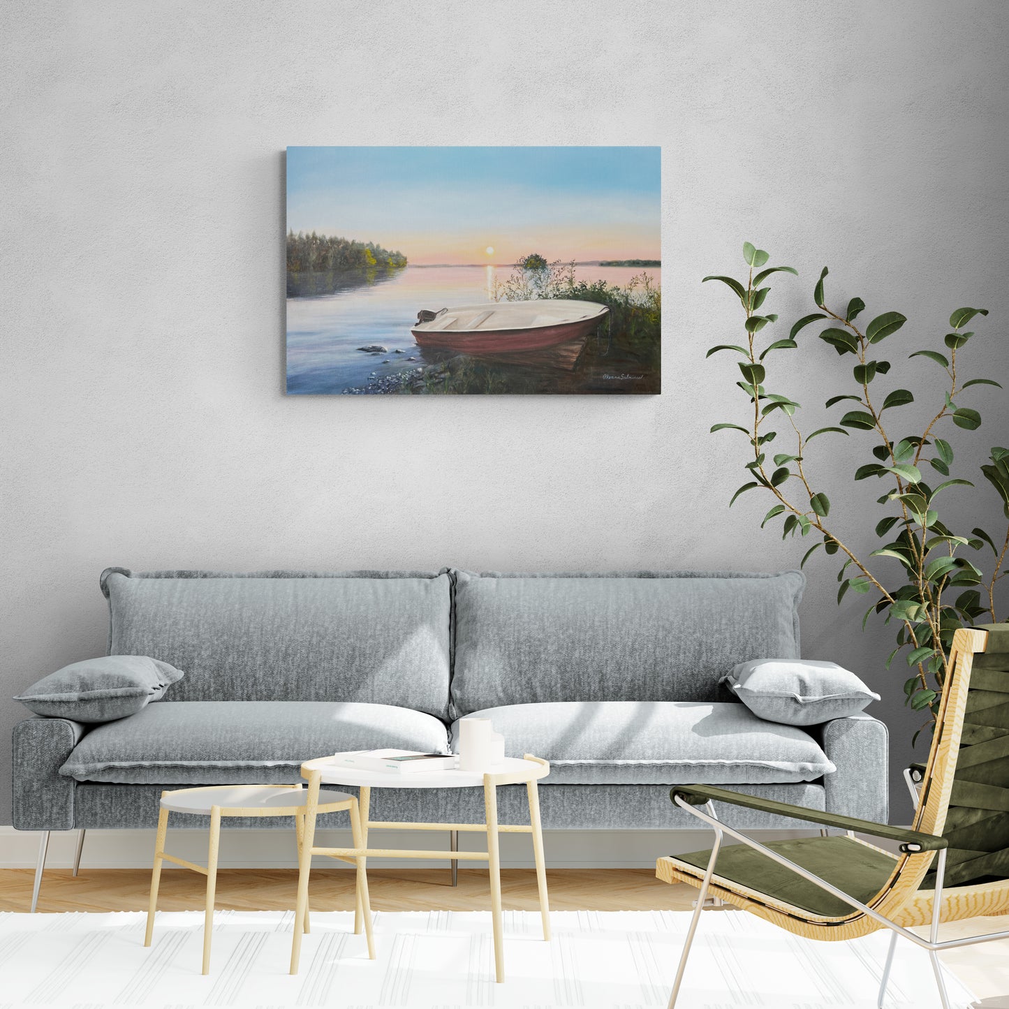 Living room with a gray sofa, small table, and chair, featuring a painting of a lake and boat on the wall.